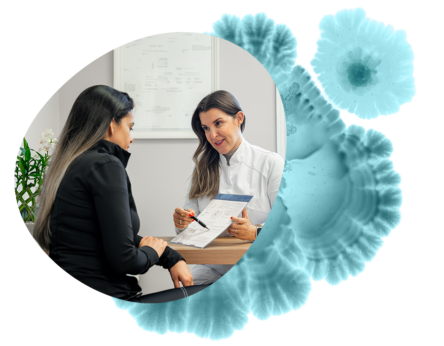 A wellness clinician holding a sheet of paper and pointing with a pen explains treatment prices and policies regarding insurance.  