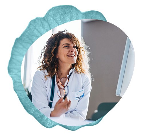 A Functional Medicine clinician sitting behind a desk smiles during a conversation with a patient.
