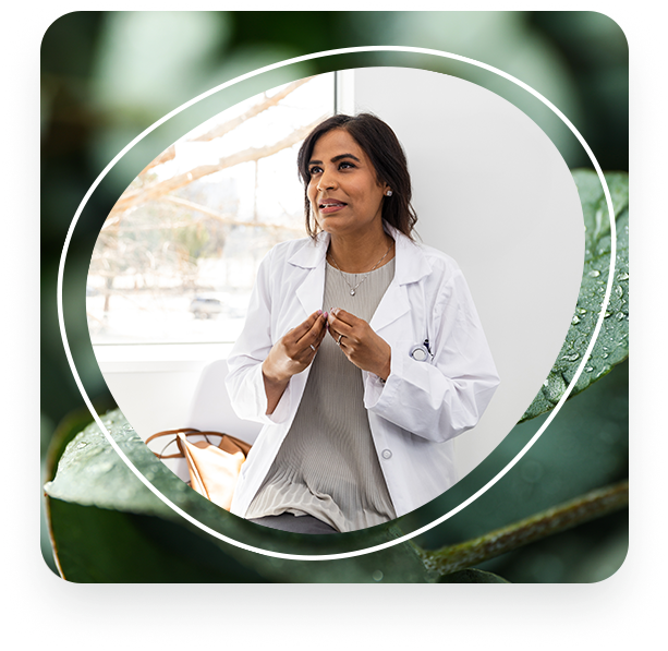 A wellness provider with dark hair and wearing a white coat explains a treatment plan with a patient.